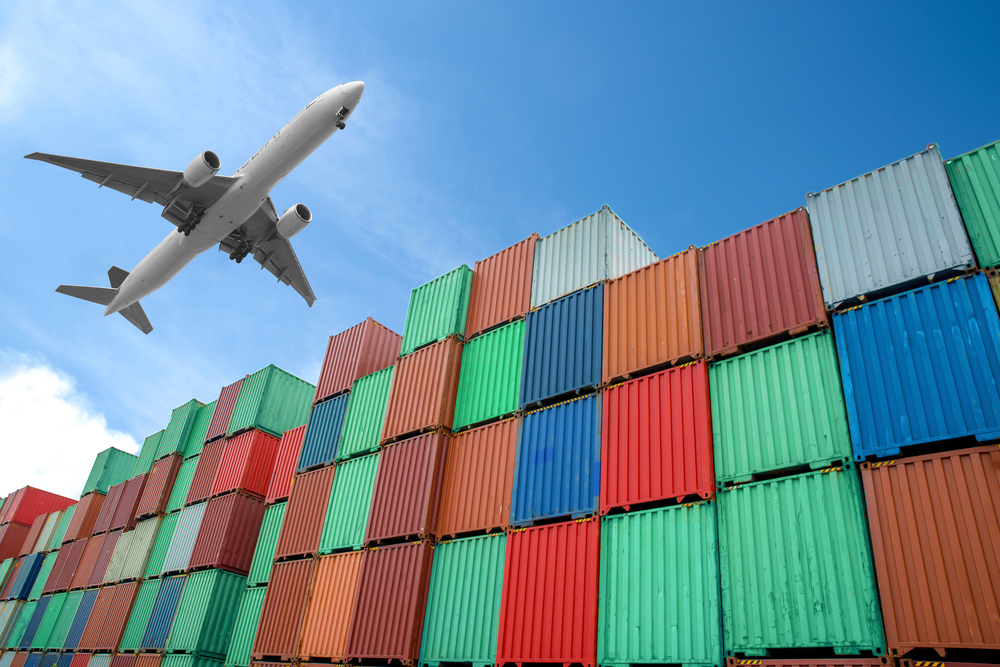 Plane flying over stacks of shipping containers